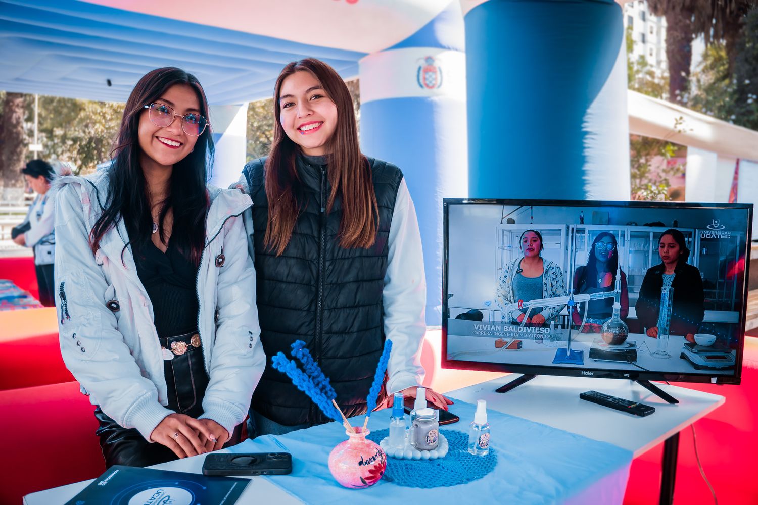 Estudiantes de UCATEC en una feria con una pantalla sobre Ingeniería Mecatrónica
